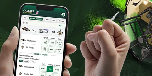 Screenshot of the Caesars Sportsbook mobile app showing NFL betting odds for the Baltimore Ravens vs. New Orleans Saints game, with a hand holding the phone and a football helmet in the background.